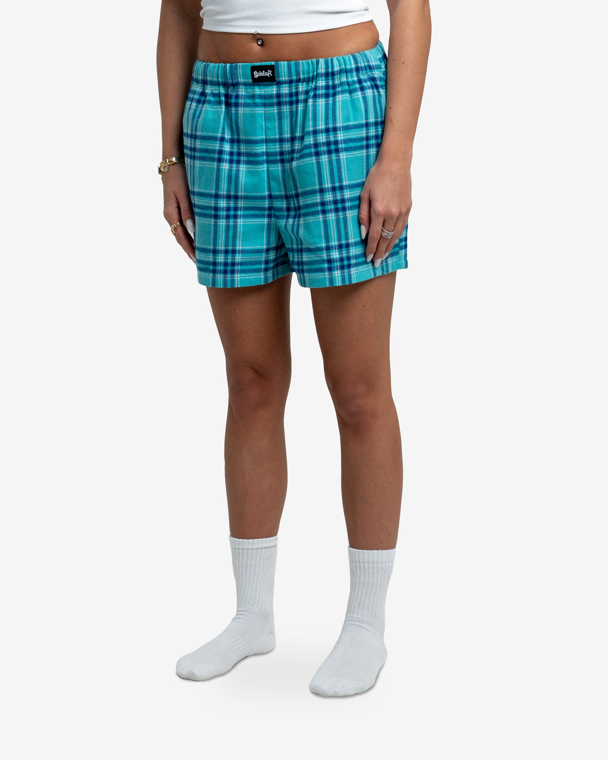 Nahaufnahme der Hot Pants Blueberry. Das Karomuster in Blautönen ist gut erkennbar, der elastische Bund ist leicht gerafft. Mittig am Bund sitzt ein schwarzes Label mit weißem „Schlafi“-Schriftzug.
