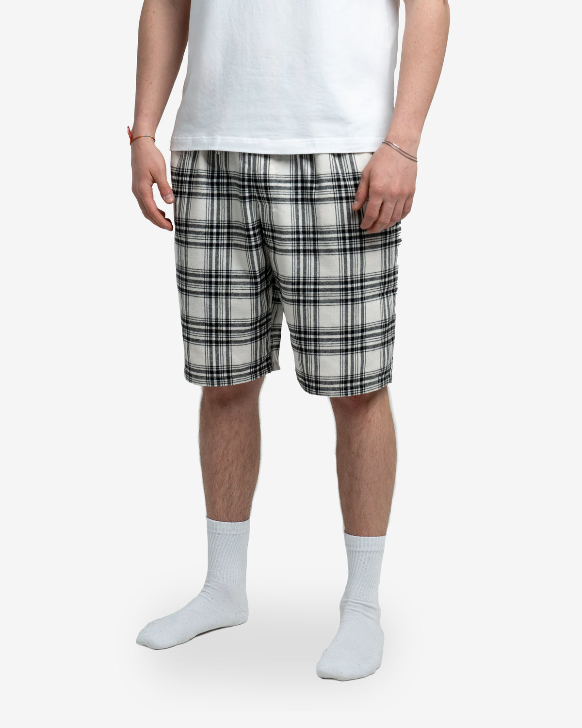 Detailansicht der Schorti in Creme mit schwarzem Karomuster. Fokus auf Schnitt, Musterverlauf und die seitlichen Taschen. Nur der untere Bauch- und Beinbereich des Modells sichtbar.