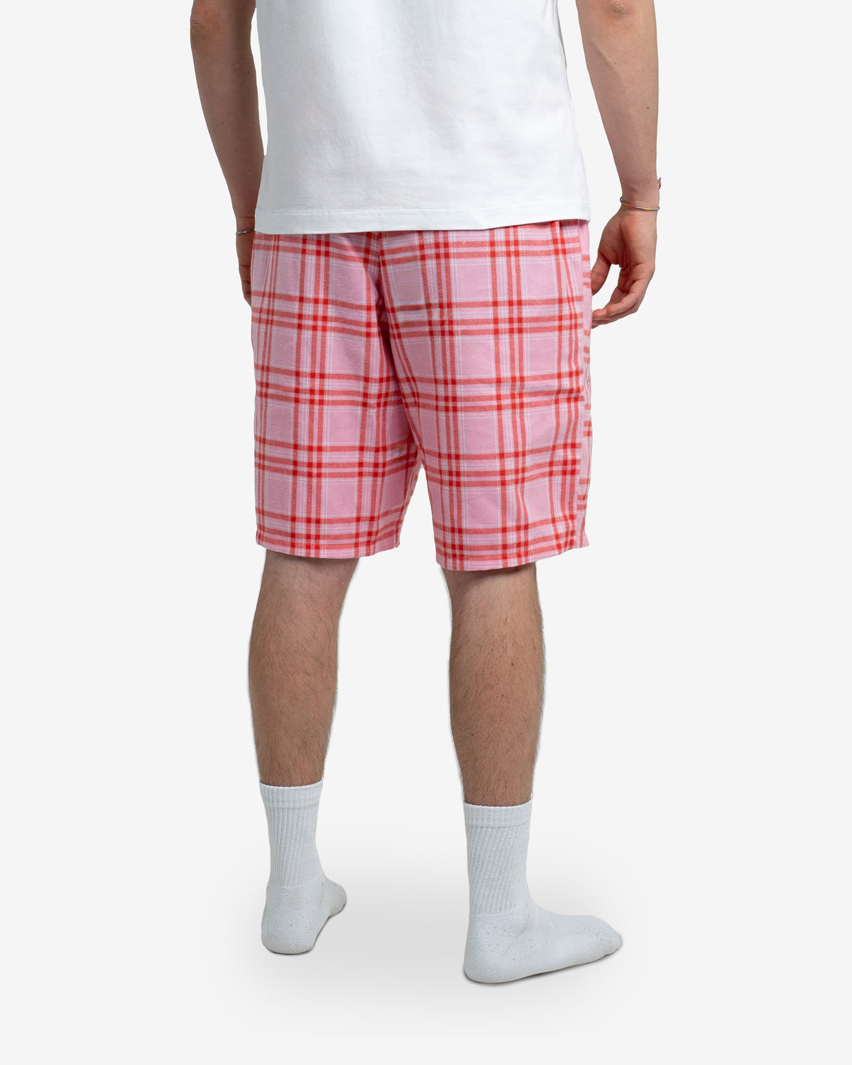 Rückansicht der Schorti in Dragonfruit. Model steht mit dem Rücken zur Kamera, trägt ein weißes T-Shirt. Fokus auf Passform und Rückansicht der Shorts, inklusive Bundhöhe. Weiße Socken. Neutraler Hintergrund.