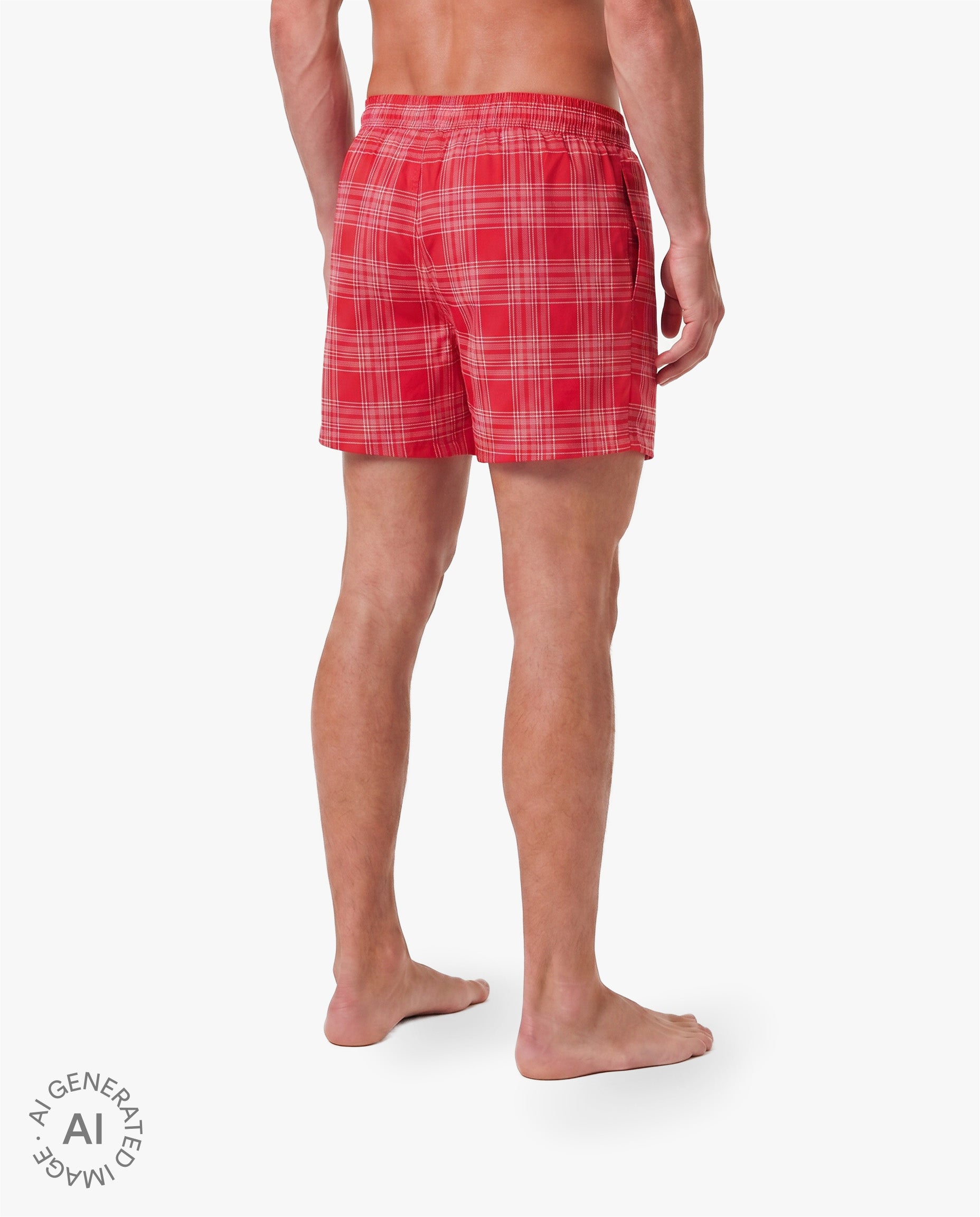 Alttext: Rückansicht eines männlichen Models in roten Badeshorts mit feinem Karomuster in Rosa und Weiß. Die Shorts haben einen elastischen Bund und eine lockere Passform. Freigestellte Produktaufnahme vor grauem Hintergrund.