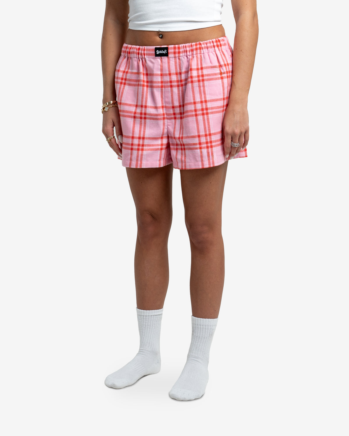 Nahaufnahme der Hot Pants Dragonfruit. Das rosa-rote Karomuster ist deutlich sichtbar, ebenso das schwarze Markenetikett auf dem Bund. Der elastische Bund ist leicht gerafft und sorgt für angenehmen Tragekomfort.