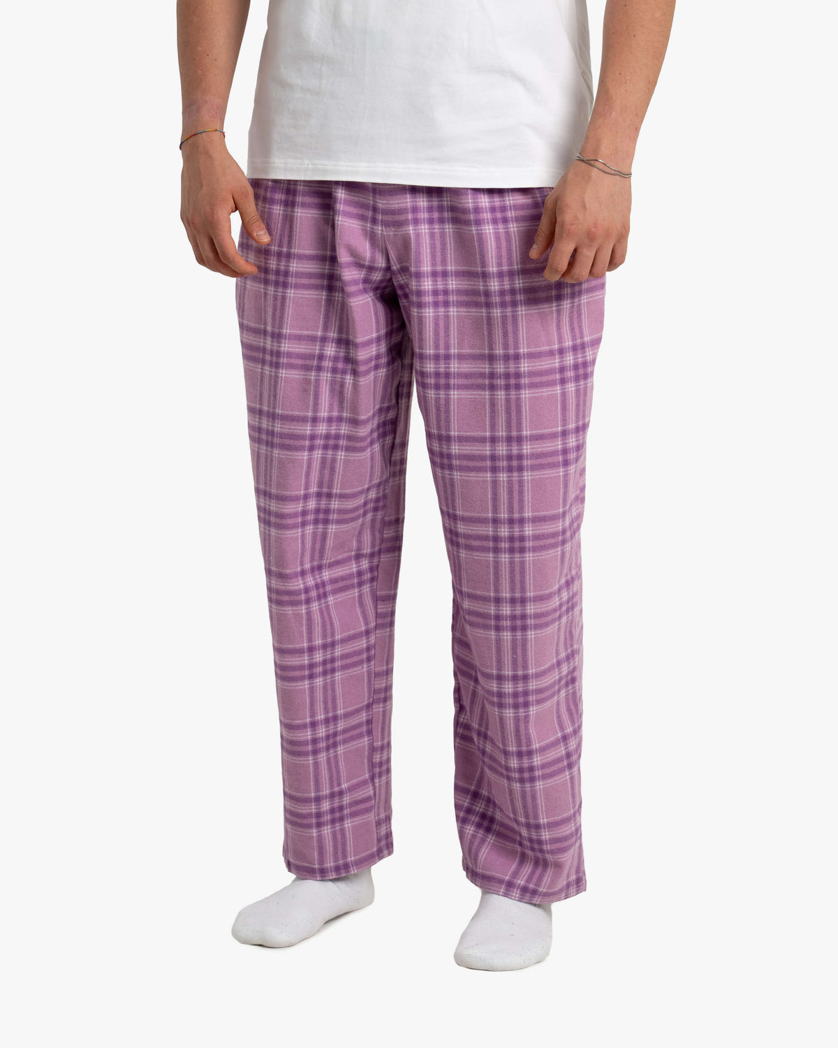 Ausschnitt der Wildberry-SCHLAFI-Hose auf Hüft- bis Knöchelhöhe. Deutlich sichtbar ist das flauschige Karomuster in Lila, Violett und Hellrosa. Der Stoff wirkt weich und gemütlich. Dazu ein schlichtes weißes T-Shirt, die Hände hängen locker herab
